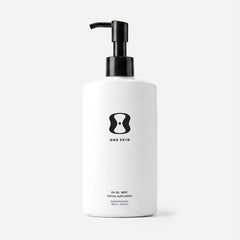 White bottle with black pump and 'One Skin' logo on a beige background