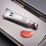 Lip balm tube with a swatch of pink lip balm on a metallic surface