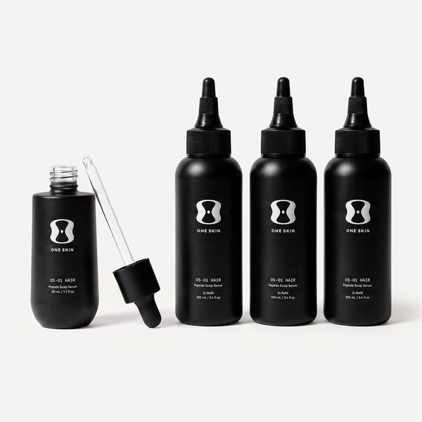 Set of black hair serum bottles with dropper on a light beige background. Contains descriptive text stating Bottle size may vary. The 6-month supply will always come with 150mL of the OS-01 HAIR serum.