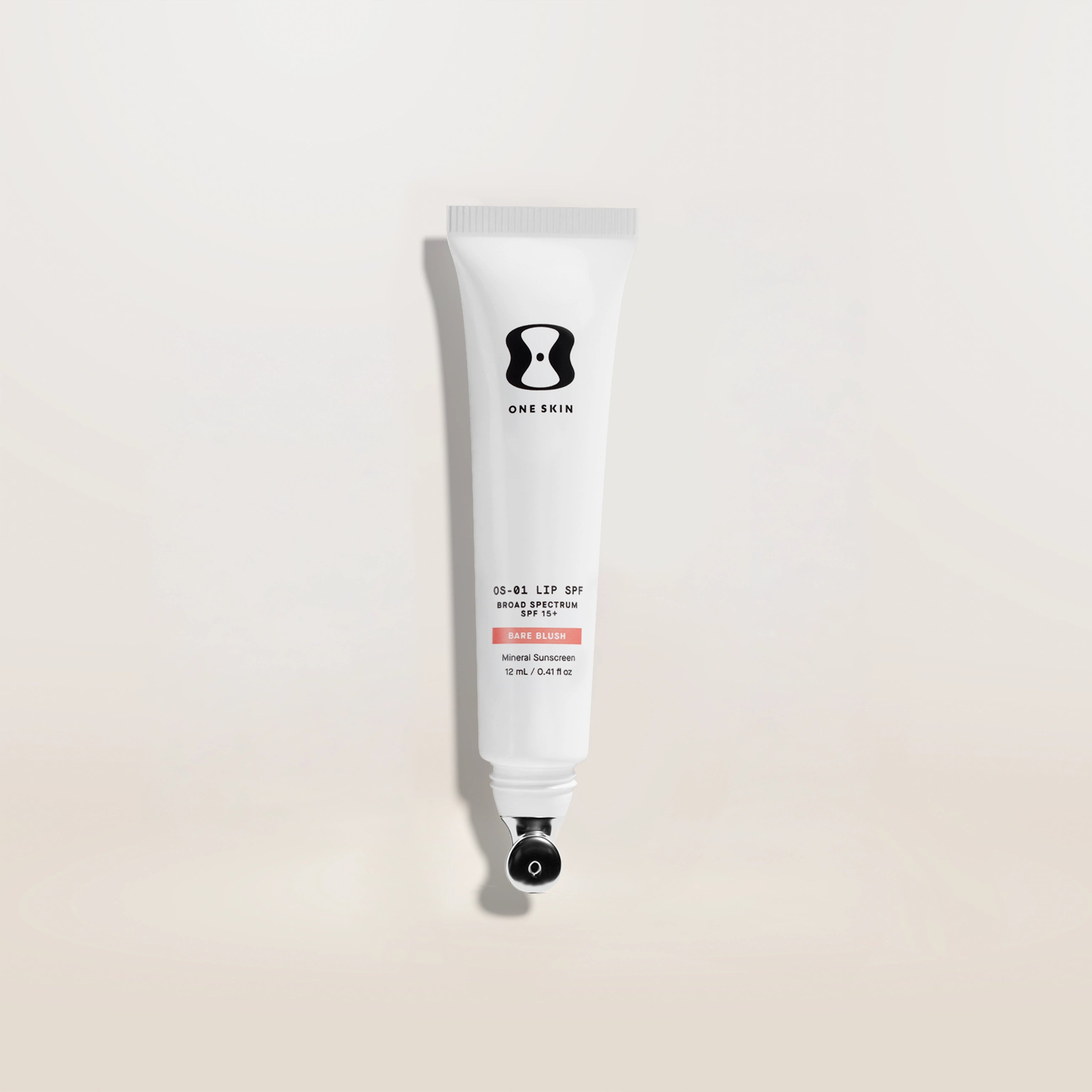 Tube of One Skin sunscreen on a light beige background