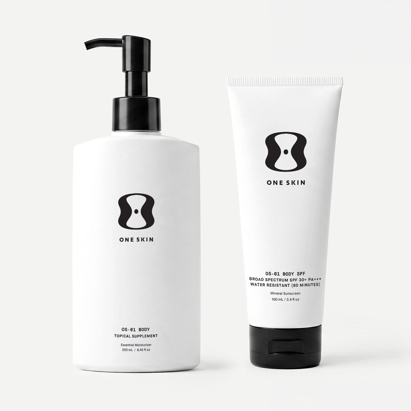 A white pump bottle and a white squeeze tube with black caps and black printed ONE SKIN branding, shown on a clean light gray studio background.