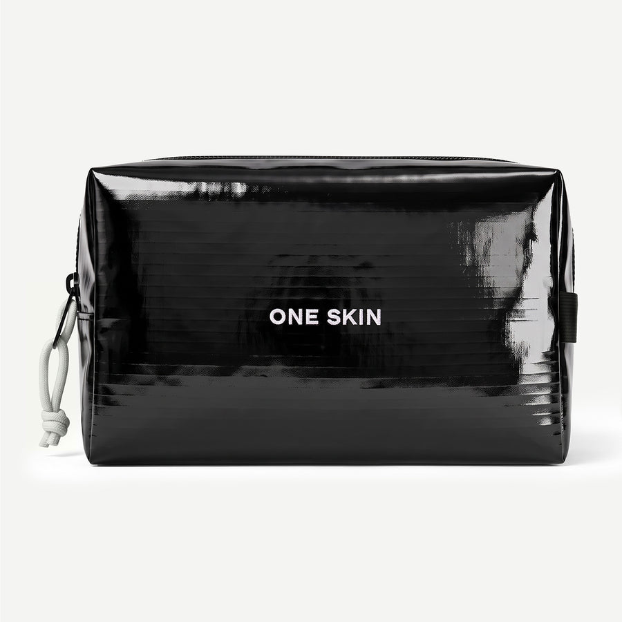 A glossy black cosmetic pouch with the brand name 'ONE SKIN' printed in white on the front, shown against a light gray background.