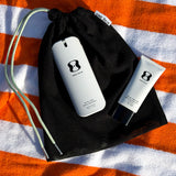 Skincare products with a black drawstring bag on an orange and white striped background