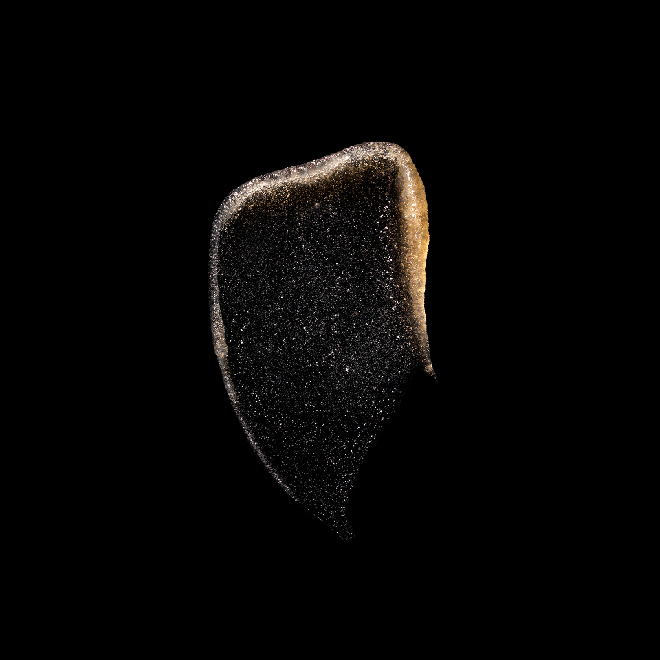 A single irregular dark brown to black textured piece, resembling a dried mushroom cap or a piece of dark cured meat, isolated on a solid black background.