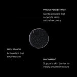 A black cosmetic jar or bottle with a clear circular lid showing a dark speckled cream inside, centered on a black background with white text labels reading PRICKLY PEAR EXTRACT, BREU BRANCO, and NIACINAMIDE.