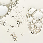Close-up of clear, transparent bubbles with thin rims floating on a very light warm off-white background.