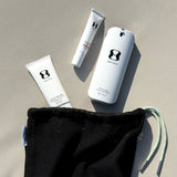 Three skincare products with a black drawstring bag on a beige surface