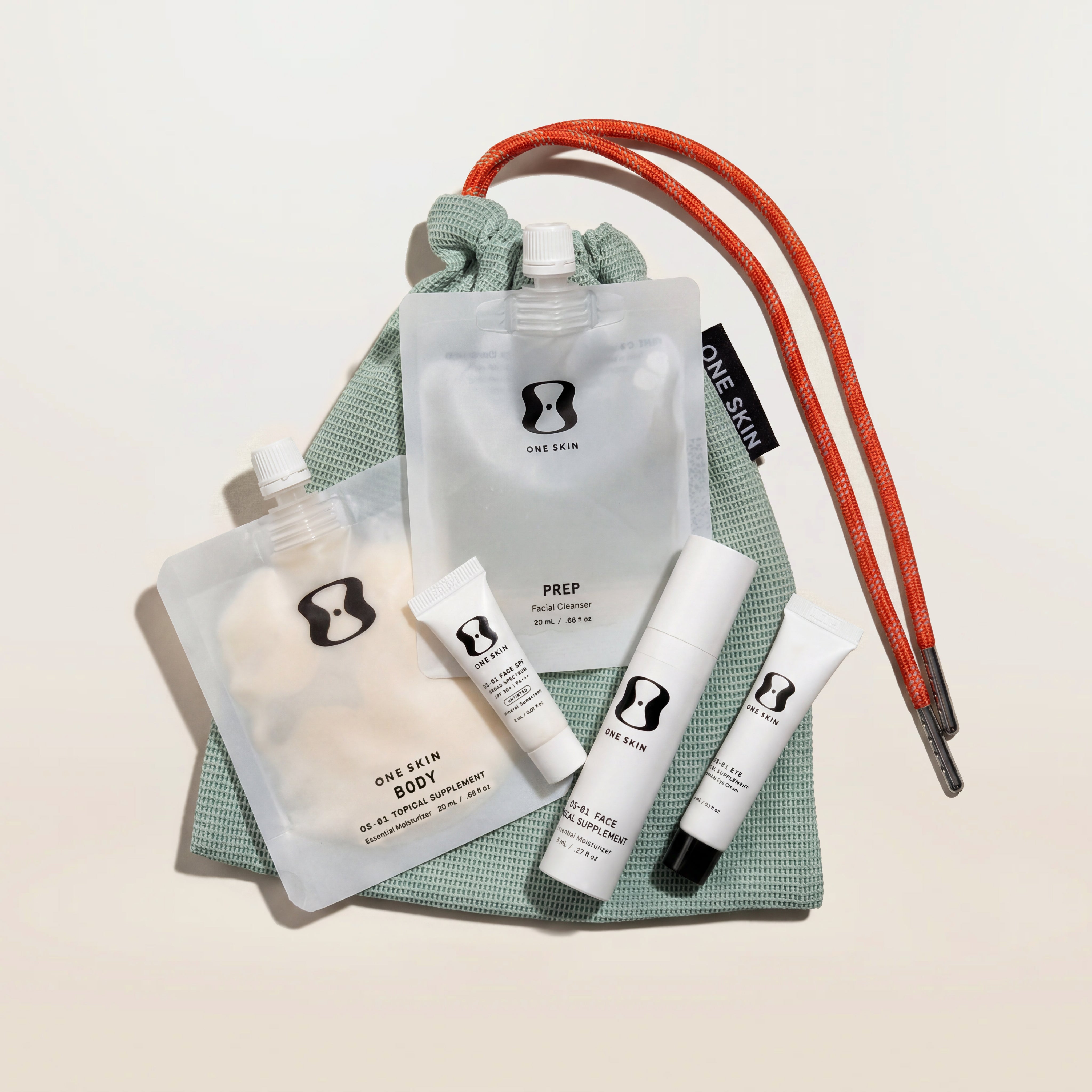 OneSkin products and a green travel bag on a beige background