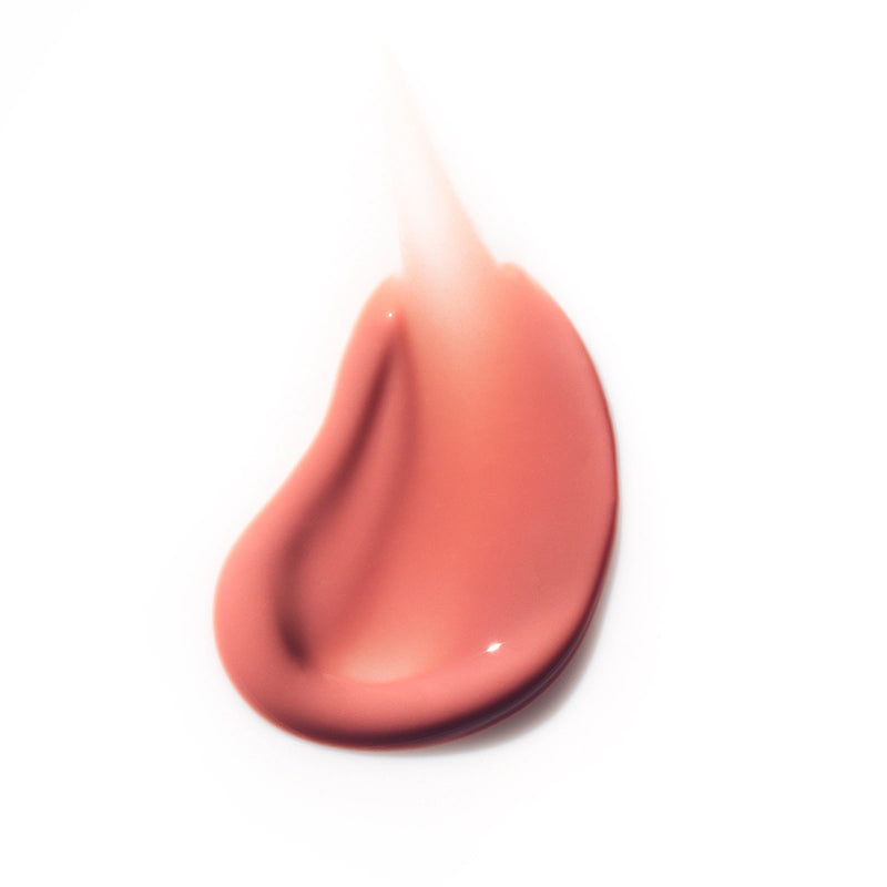 Close-up of a peach-colored lip gloss on a white background