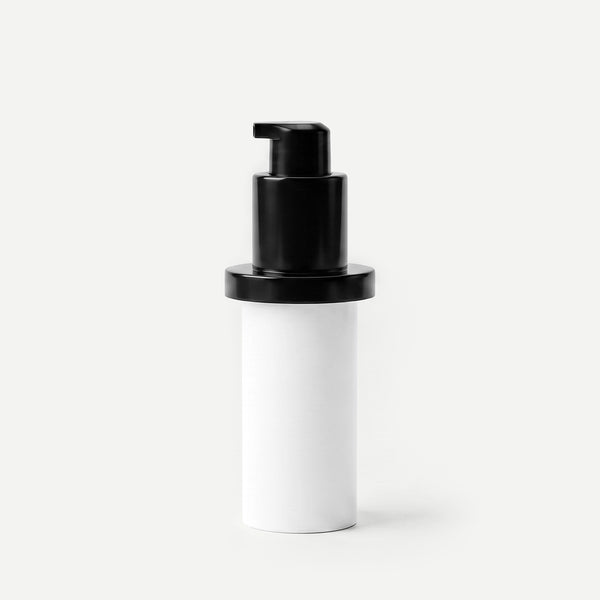 White cylindrical container with a black pump on a beige background