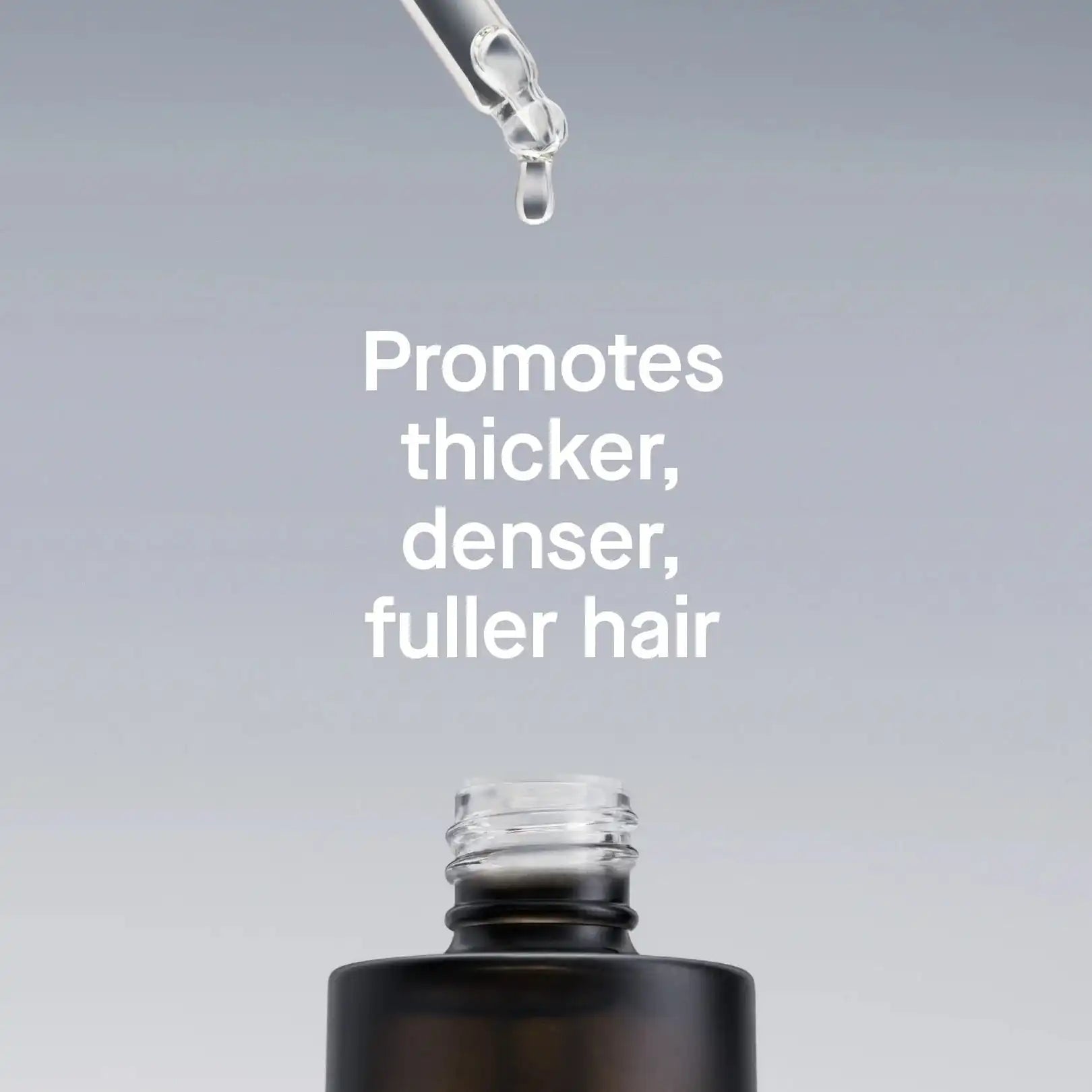 Hair product dropper with text promoting thicker, denser, fuller hair on a gray background