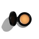 Open compact with beige cream on a white background