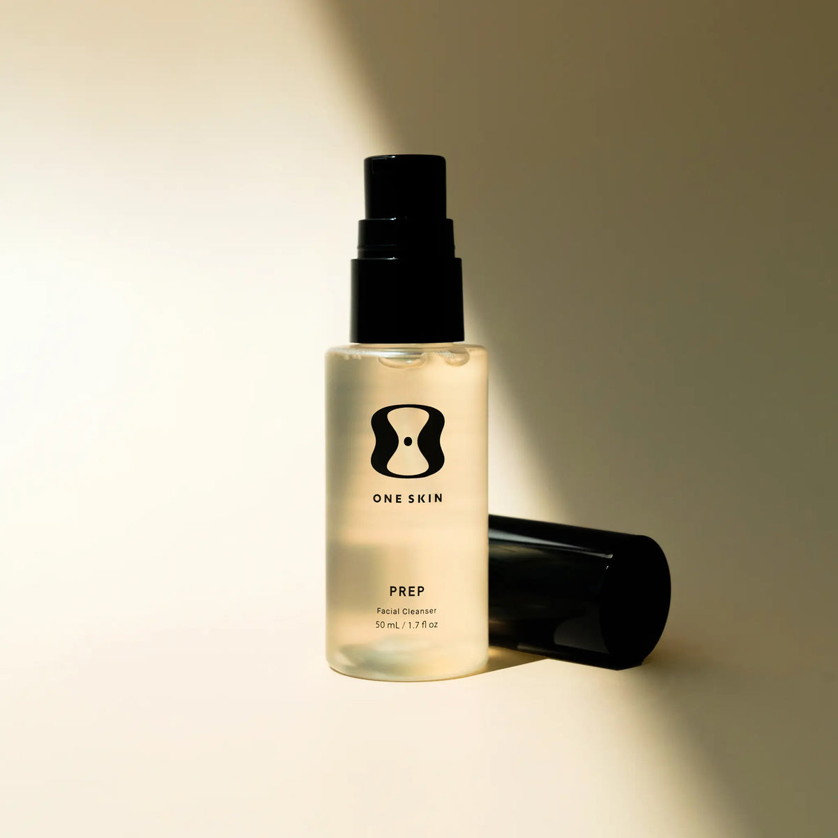 Skincare bottle labeled 'ONE SKIN' on a beige background