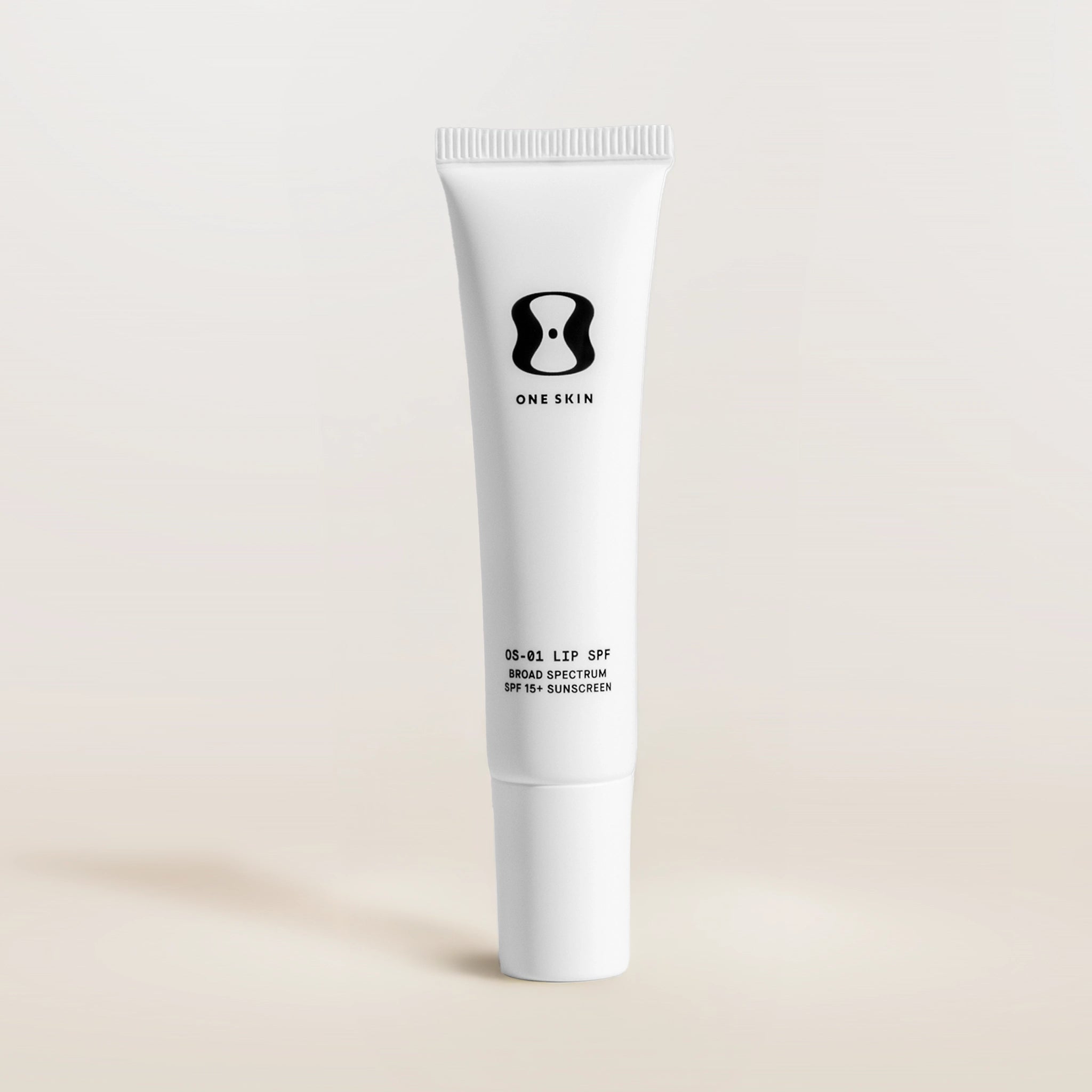 White tube of One Skin lip SPF on a beige background
