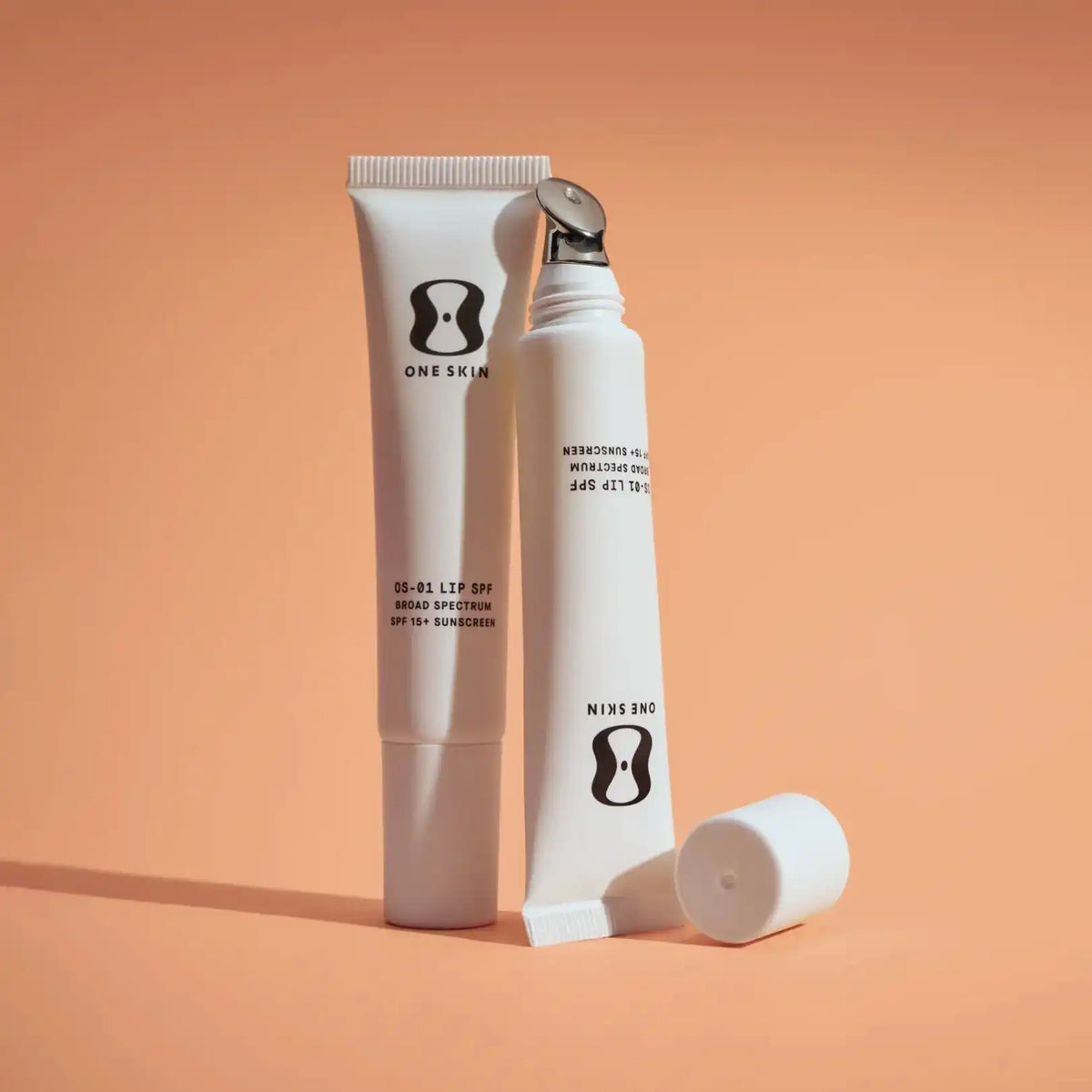 Two skincare products with 'ONE SKIN' branding on an orange background